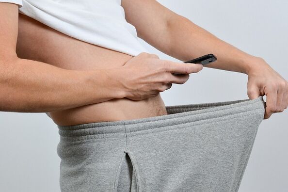 A man looks down at his pants to see his penis enlarged